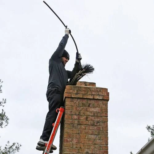 A chimney sweep using a long flexible rod above a brick chimney